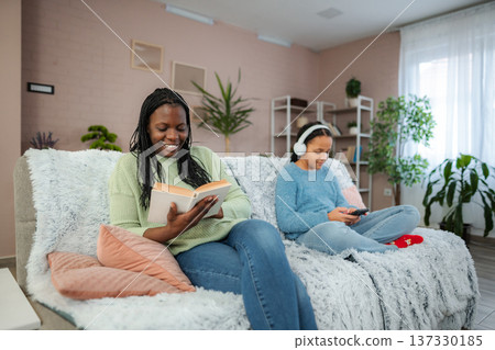 Enjoying a cozy afternoon filled with books and technology in a stylish modern living room with friends 137330185
