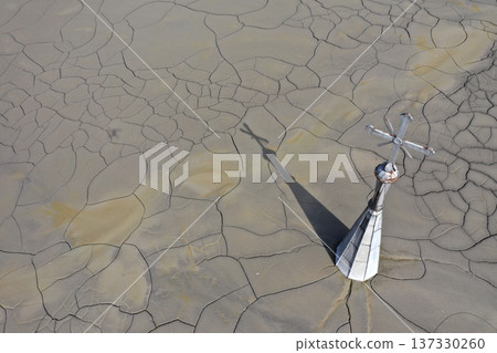 Aerial view of a sinking church in a decanting lake, tower with cross raising over mud, 137330260