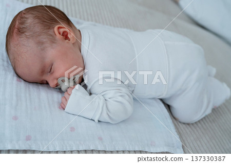 Newborn baby sleeping on soft bedding at home. Quiet domestic scene. Concept of early parenting, childcare, family routine and healthy infant development. Newborn baby sleeping on soft bedding at home. Quiet domestic scene. Concept of early parenting, childcare, family routine and healthy infant development. 137330387
