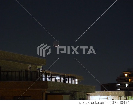 A crescent moon setting over the city 137330435