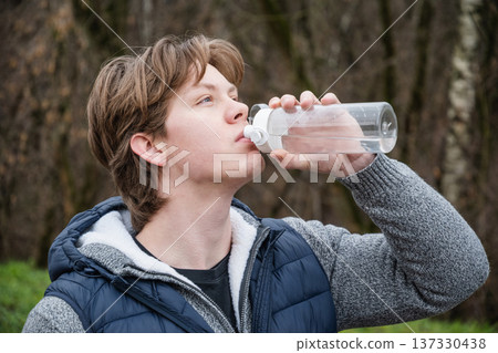 Sporty man drinking water from bottle at public park after workout. Sporty man drinking water from bottle at public park after workout. 137330438