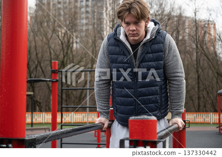 Man Performing Dips on Parallel Bars Outdoors. Training Outdoors 137330442