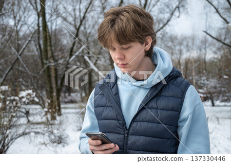 Man using phone in winter park. Outdoor Lifestyle 137330446