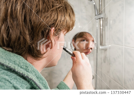 Man Using Electric Trimmer for Grooming in Bathroom 137330447