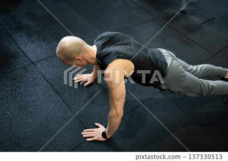 Athletic man doing push ups on gym floor 137330513
