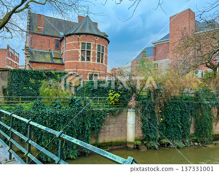 Scenic canal in Leuven framed by green hedges and historic red brick buildings Scenic canal in Leuven framed by green hedges and historic red brick buildings 137331001