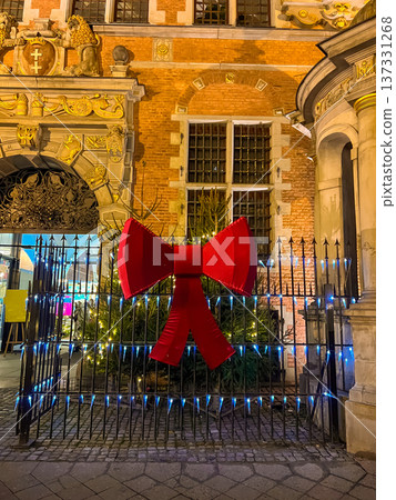 Bright red bow decoration on gate with Christmas tree in city at night Bright red bow decoration on gate with Christmas tree in city at night 137331268