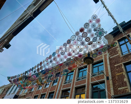 Vibrant circular art instalation hanging from historical building roof in Leuven Vibrant circular art instalation hanging from historical building roof in Leuven 137331629