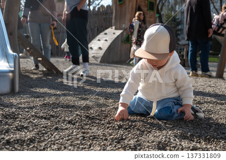 Toddler playing on gravel playground in sunny park Toddler playing on gravel playground in sunny park 137331809