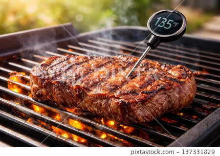 Juicy Grilled Steak Cooking on Barbecue Grill with Digital Meat Thermometer Showing Perfect Temperature 137331829
