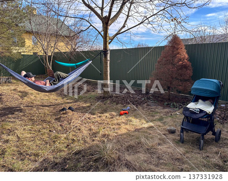 Person relaxing in hammock in backyard with stroller 137331928
