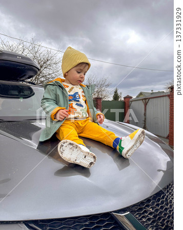 Toddler Sitting on Hood of Gray Suv in Driveway Toddler Sitting on Hood of Gray Suv in Driveway 137331929