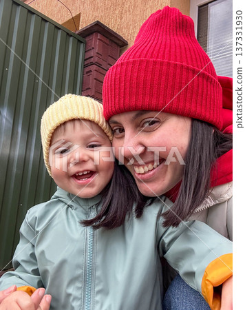 Smiling mother and toddler in winter beanies outdoor selfie Smiling mother and toddler in winter beanies outdoor selfie 137331930