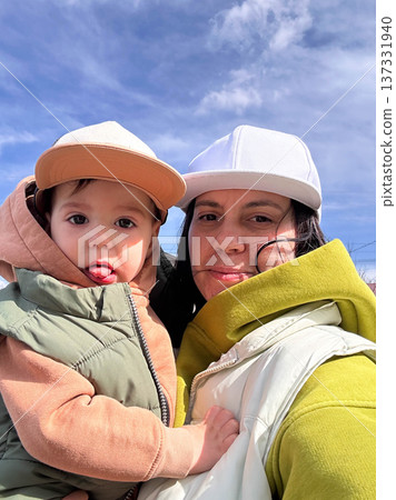 Mother holding toddler outdoors under blue sky Mother holding toddler outdoors under blue sky 137331940