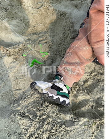 Child sneaker in beach sand with toy shovel Child sneaker in beach sand with toy shovel 137331941