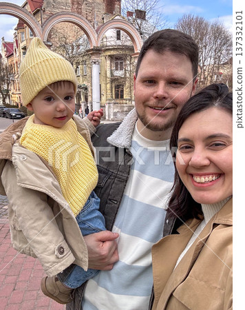 Happy family selfie in park with toddler wearing yellow beanie Happy family selfie in park with toddler wearing yellow beanie 137332101