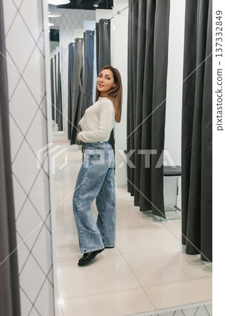 Woman trying denim in fitting room store Woman trying denim in fitting room store 137332849