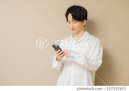 看他的智能手機的一個年輕人 看他的智能手機的一個年輕人 137332921