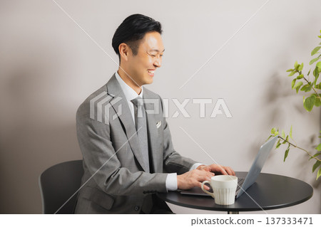 A businessman looking at a computer while drinking coffee 137333471