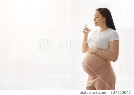 Pregnant woman drinking water at home to stay hydrated during pregnancy Pregnant woman drinking water at home to stay hydrated during pregnancy 137333642