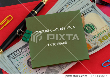 Olive note inspiring progress rests on US currency, with a pen clips on a red desk Olive note inspiring progress rests on US currency, with a pen clips on a red desk 137333863