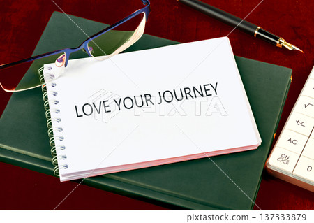 LOVE YOUR JOURNEY notebook on dark green book, with glasses, fountain pen, and calculator on a deep red table LOVE YOUR JOURNEY notebook on dark green book, with glasses, fountain pen, and calculator on a deep red table 137333879