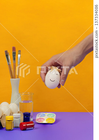 SSTK Easter. Playful hand holding a decorated Easter egg with a smiley face. SSTK Easter. Playful hand holding a decorated Easter egg with a smiley face. 137334086