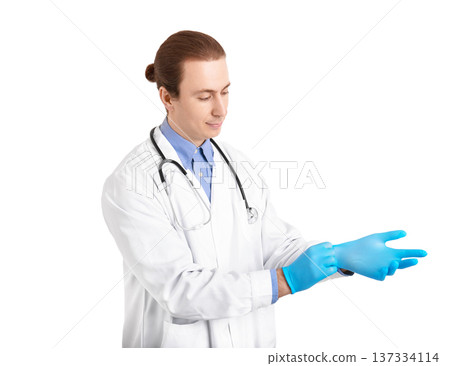 Male doctor in a white coat putting on blue medical gloves. Professional healthcare worker preparing for a procedure or examination isolated on a white background. High quality photo Male doctor in a white coat putting on blue medical gloves. Professional healthcare worker preparing for a procedure or examination isolated on a white background. High quality photo 137334114