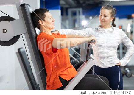Senior woman exercising chest press with personal trainer Senior woman exercising chest press with personal trainer 137334127