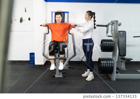 Senior woman exercising with coach at gym 137334133