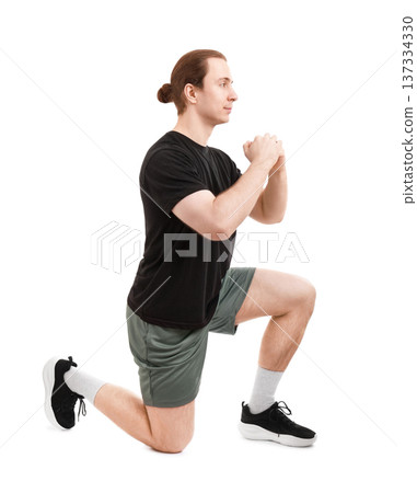 Side view of a fit young man with a hair bun performing a lunge exercise during a workout. Isolated on white background. High quality photo 137334330