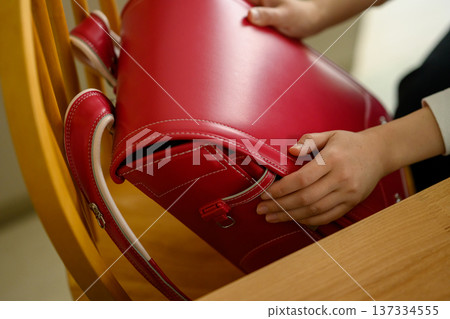 A red school bag held in hand 137334555