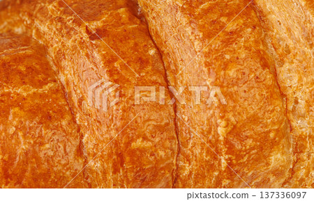 Extreme close up of crispy croissant texture. Macro shot of golden brown flaky puff pastry surface. 137336097