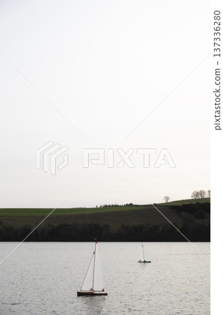 Two radio controlled sailboats racing on lake, vertical format Two radio controlled sailboats racing on lake, vertical format 137336280