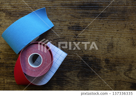 Red and blue kinesiology tape strips on wooden background Red and blue kinesiology tape strips on wooden background 137336335