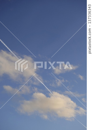 Airplane trail in the blue sky, white clouds on a sunny day 137336343