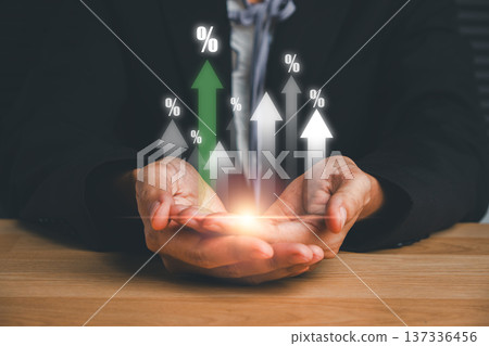 Hands of a businessman holding glowing arrows with percentage signs, representing financial growth and success. 137336456