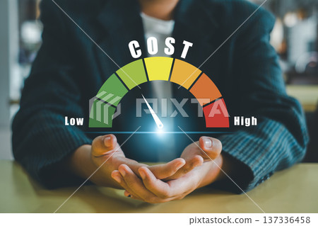Businessman holding a cost gauge showing low to high indicator, symbolizing financial analysis and budget planning. 137336458