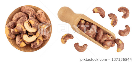 cashew nut with shell in wooden bowl and scoop isolated on white background. Top view. Flat lay 137336844