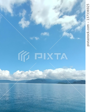 A calm lake and white clouds under a blue sky 137336925
