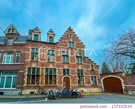 Charming old red brick building in Leuven surrounded by trees and bicycles Charming old red brick building in Leuven surrounded by trees and bicycles 137337014