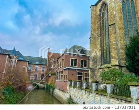 Gothic church and historic town houses in Leuven with canal under blue sky Gothic church and historic town houses in Leuven with canal under blue sky 137337031
