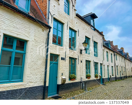 Charming old townhouse exterior with white brick, blue windows, and teal doors Charming old townhouse exterior with white brick, blue windows, and teal doors 137337049