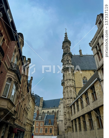 Old street view of Leuven town hall with ornate buildings and church tower 137337119