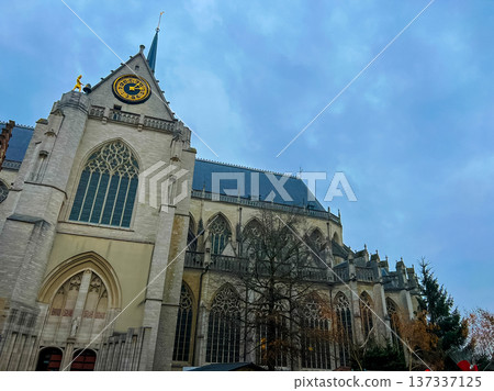 Stunning view of Leuven cathedral with ornate clock over a blue sky with clouds 137337125