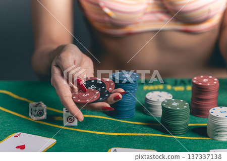 Woman Holding Poker Chips at Casino Table with Colorful Chips and Playing Cards for Gambling Lifestyle and Entertainment Concept 137337138