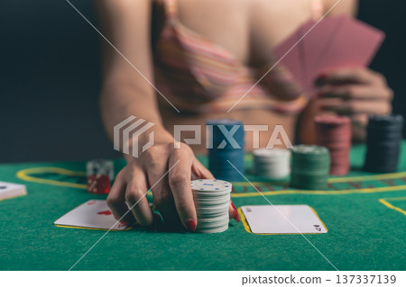 Woman in Casual Attire Engages in Intense Card Game with Poker Chips and Cards on Green Felt Table, Capturing Strategic Moment of Play Woman in Casual Attire Engages in Intense Card Game with Poker Chips and Cards on Green Felt Table, Capturing Strategic Moment of Play 137337139