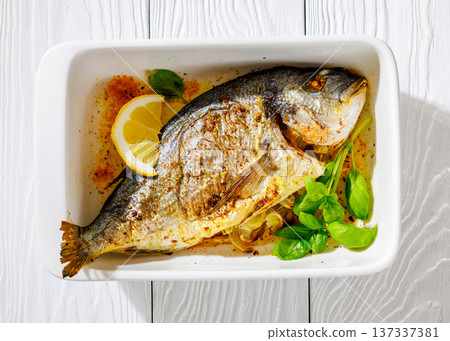Baked whole dorada fish with lemon and basil 137337381