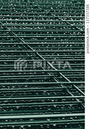 Metal grille with water droplets glistening. Rainy atmosphere, perfect for urban or industrial themes. Suggests freshness, renewal, or quiet moments. Ideal for backgrounds, mood boards, or design Metal grille with water droplets glistening. Rainy atmosphere, perfect for urban or industrial themes. Suggests freshness, renewal, or quiet moments. Ideal for backgrounds, mood boards, or design 137337386