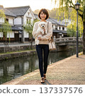 一位年輕苗條的女子帶著她的狗在岡山美麗歷史街區的街道上擺姿勢拍照。 137337576